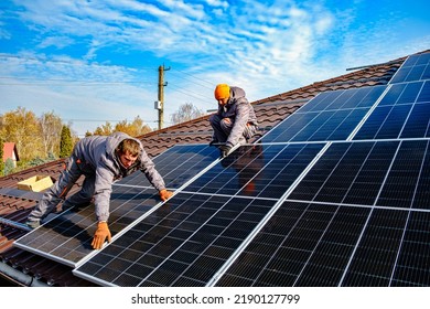 Solar panel technician installing solar panels on roof. technician in blue suit installing photovoltaic blue solar modules. Electrician panel sun sustainable resources - Shutterstock ID 2190127799