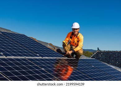 Solar Panel Technician With Power Meter And Solar Panels On House Roof.