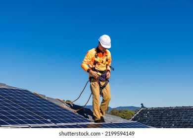 Solar Panel Technician With Power Meter And Solar Panels On House Roof.