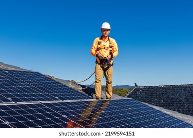 Solar Panel Technician With Power Meter And Solar Panels On House Roof.