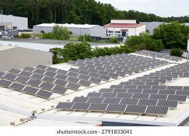 Solar panels array installed on a corrugated metal roof of an industrial warehouse, generating green renewable energy.