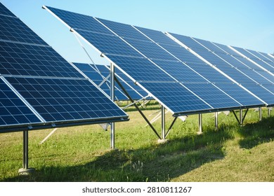 Solar panels converting sunlight into electricity, standing on a green field under a clear blue sky, demonstrating sustainable energy