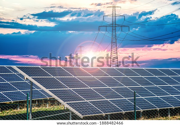 Solar panels with electricity pylons at sunset , \
power plant