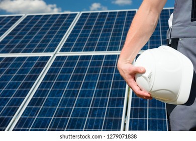 Solar Panels Engineer Holding White Protective Cask, Hand Close, Solar Pannel Field Background. Hot Sunny Summer Weather. Copy Space. Concept Of Renewable And Clean Energy, Technology.