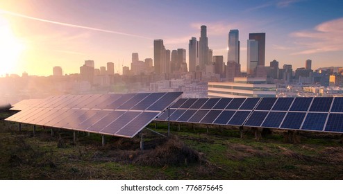 Solar Panels Front Of Big City On Sunset. Industrial Landscape With Photovoltaic Power Plant. Environmental Concept. Solar Farm Produces Alternative Green Energy. Photovoltaic Cells 