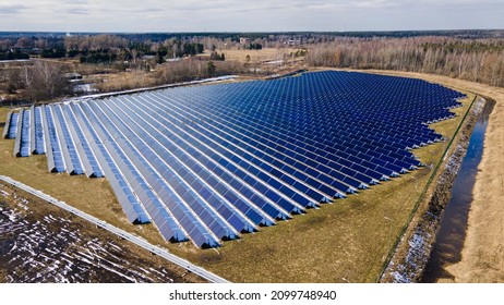 Solar Panels Grid In Solar Farm. Spring Day After Winter Snow. Solar Power Green Energy. Renewable Energy To Stop Climate Change. Sustainable Electricity Sources. Aerial Fly Over Drone Shot.  