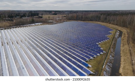 Solar Panels Grid In Solar Farm. Spring Day After Winter Snow. Solar Power Green Energy. Renewable Energy To Stop Climate Change. Sustainable Electricity Sources. Aerial Fly Over Drone Shot.  