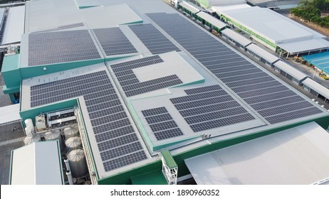 Solar panels installed on a roof of a large industrial building or a warehouse. Industrial buildings in the background. Horizontal photo.