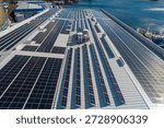 Solar panels installing on a large industrial building roof next to a harbor generating clean energy