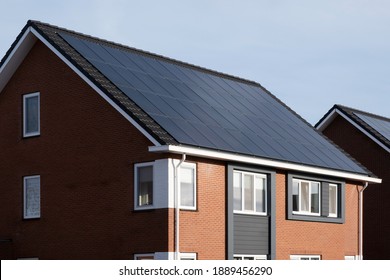 Solar panels mounted on the roof of a modern new-build house with red roof tiles in Lemmer, Friesland, the Netherlands with blue skies. Sustainable, renewable energy