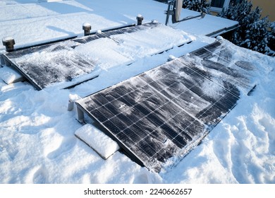 Solar panels on the roof are cleaned from snow with a broom - Shutterstock ID 2240662657