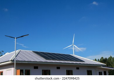 Solar panels on the roof and there are also wind turbines around. The concept of renewable and sustainable resources. - Powered by Shutterstock