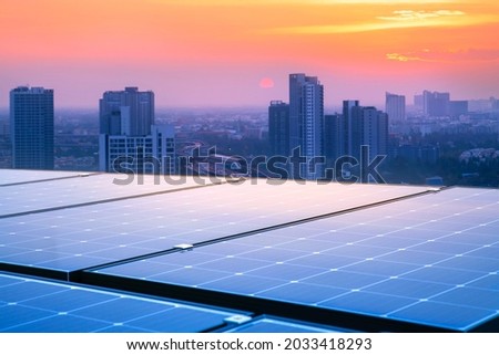 Solar panels on the rooftops of tall buildings reflect the sunset. Modern cities and traffic are the backgrounds. Sustainable renewable energy. Modern energy concepts for housing and transportation