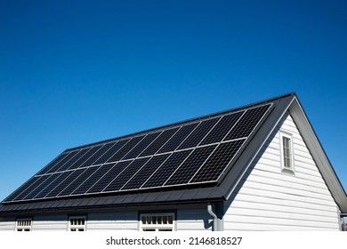 Solar panels on small wood board domestic house roof, sustainable energy concept. Lot of copy space on clear blue sky. - Shutterstock ID 2146818527
