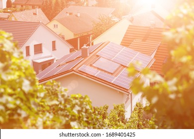 Solar panels on the tiled roof of the building in the sun. Top view through grape leaves. Image for illustration on energy, self-reliance, autonomy and security. - Shutterstock ID 1689401425