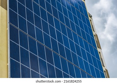 Solar Panels On The Wall Of A Multi-storey Building On Storm Clouds Background. Renewable Solar Energy. An Energy-efficient Home That Uses The Energy Of The Earth, Sun, Air And Wastewater