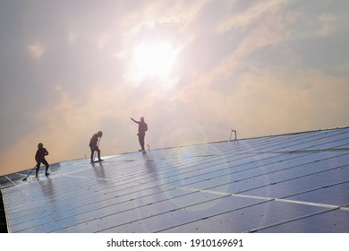 Solar Panels Or Photovoltaic Panels Installed On The Roof Of The Building Which Were Washing The Surface By Workers To Get High Quality And Use Green And Clean Energy Inside The Building Below.