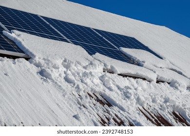 Solar panels under snow in sunny winter day.