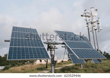 Solar panels and Wind Turbines with cloudy background