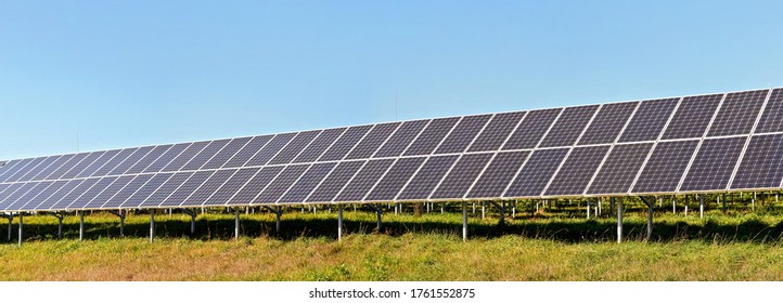 Solar Photovoltaic Panels On Green Grass Meadow, Clear Sky Above, Wide Banner Photo