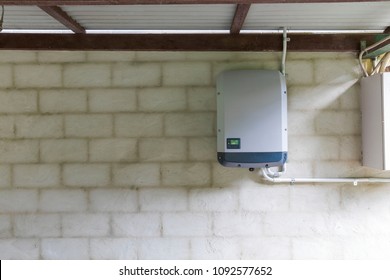 Solar power inverter mounted on brick wall inside garage, domestic system