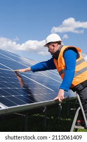 Solar power plant worker on stepladder makes a visual inspection of solar panels - Shutterstock ID 2112061409