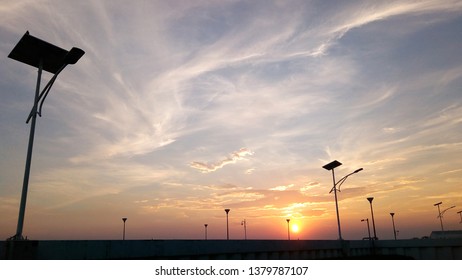 Solar Street Light Lamp Post Led With Panel System And Orange Sunset Silhouette Sky And White Clouds Using For Banner Or Background Energy Saving Concept.