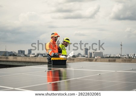 Solar Technicians examine portable testing equipment and technical documents beside rooftop photovoltaic panels while assessing a commercial renewable energy system.