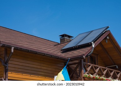 Solar thermal individual heating system for hot water on bitumen asphalt shingles roof. Brick chimney pipe on a wooden house. Rain gutter. - Shutterstock ID 2023010942