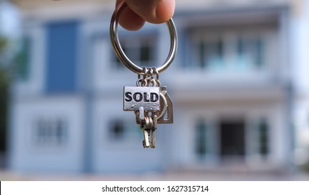 Sold House Key And Blurry Home On Background