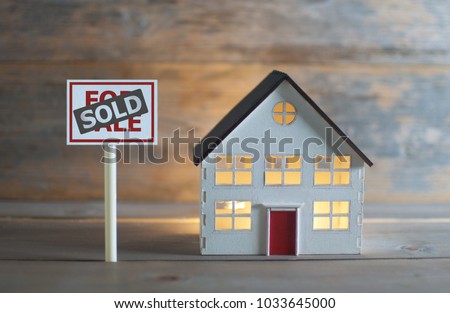 For sold sign next to a model house