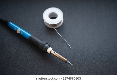 Soldering iron with tin solder on a black background.Soldering of parts. An amateur radio instrument.Electric soldering iron on the table.