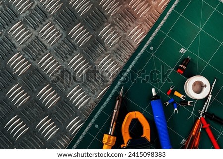 Soldering tools. Soldering iron, spool of soldering wire, screwdriver, solderless insulated spade terminals put on industrial metal checker plate and green cutting mat. Brazing equipment. Welding DIY.