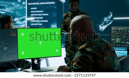 Soldier analyzing real time data next to green screen in high tech military office, processing intelligence for field operations and coordinating strategic missions to ensure national interests
