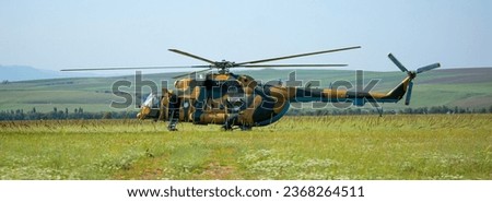 A soldier in camouflage goes to a military helicopter. Military helicopter with soldiers. Armed conflict, hostilities. Air armament, parachutist.