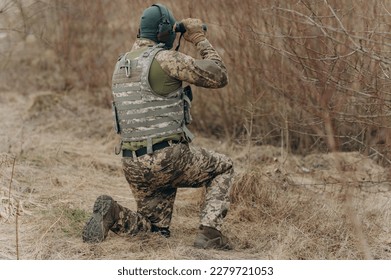 a soldier in camouflage holds binoculars. military man holding binoculars. soldier in the field - Powered by Shutterstock