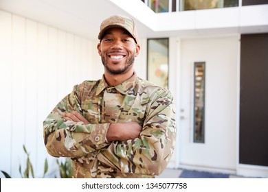 Soldier in camouflage standing outside modern house with arms crossed smiling to camera, close up - Powered by Shutterstock