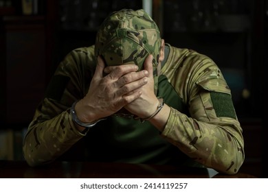 Soldier in camouflage uniform handcuffed indoors covers face, dark tone. - Powered by Shutterstock