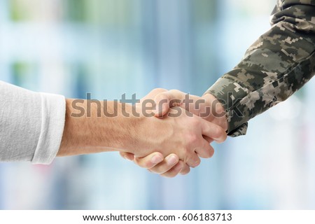 Soldier and civilian shaking hands on blurred background