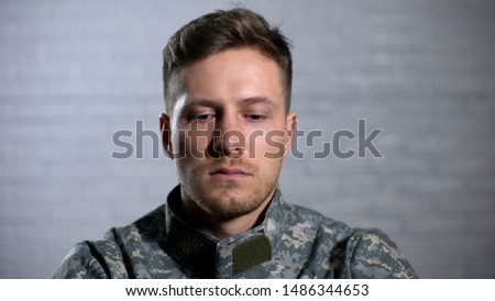 Soldier crying and looking down, remembering dead fellows and feeling hopeless