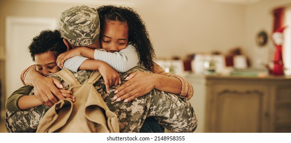Soldier embracing his wife and kids on his homecoming. Serviceman receiving a warm welcome from his family after returning from deployment. Military family having an emotional reunion. - Powered by Shutterstock