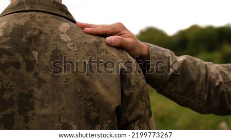 a soldier encourages another soldier by clapping him on the shoulder. instruction of an officer to a soldier. motivation in the military. a meeting of old friends after the hostilities.