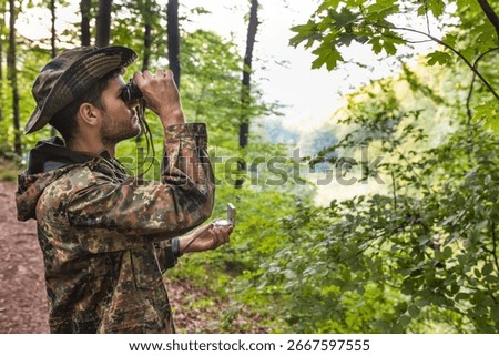 Soldier exploring forest using binoculars and compass