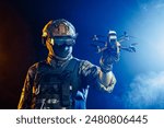 Soldier in gear holds drone against a red and blue smoky background, conveying intensity and military action