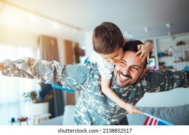 Soldier And His Little Son Hugging At Home. Smiling Soldier Reunited With His Son After Coming Back From War. Military Soldier Father With Son Kid Smiling During Home Return - Family Love US Army