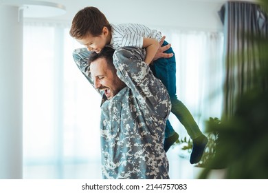 Soldier and his little son hugging at home. Smiling soldier reunited with his son after coming back from war. Military soldier father with son kid smiling during home return - Family love US army