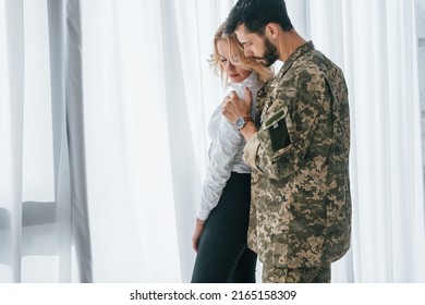 Soldier with his wife standing indoors and embracing. - Shutterstock ID 2165158309