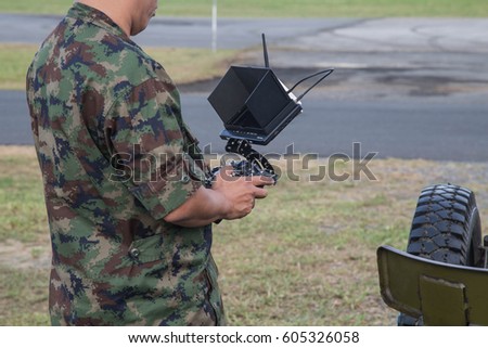 Soldier holding remote controller in hands close-up. Male hands piloting rc car, drone or helicopter. Pilot running his vehicle with transmitter outdoor, free space