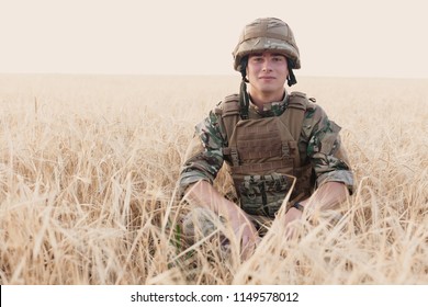 Soldier Man Standing Against A Field. Portrait Of Happy Military Soldier In Boot Camp. US Army Soldier In The Mission. War And Emotional Concept.