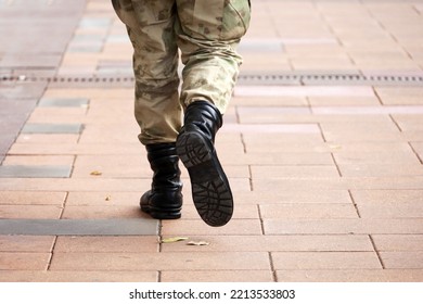 Soldier In Military Camouflage And Boots Walking Down The City Street, Legs On Sidewalk. Concept Of Service In Army, Mobilization